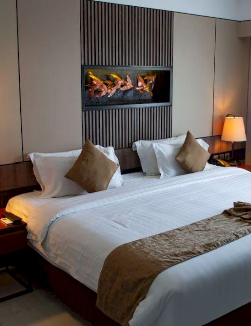 A cozy hotel room with a large bed, two nightstands with lamps, a decorative wall panel, and curtains drawn to the side.