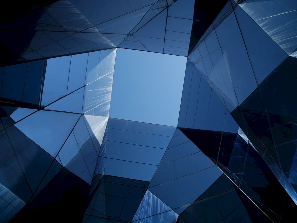 Geometric skyscrapers form an angular, reflective view of the sky, creating a dynamic architectural composition.