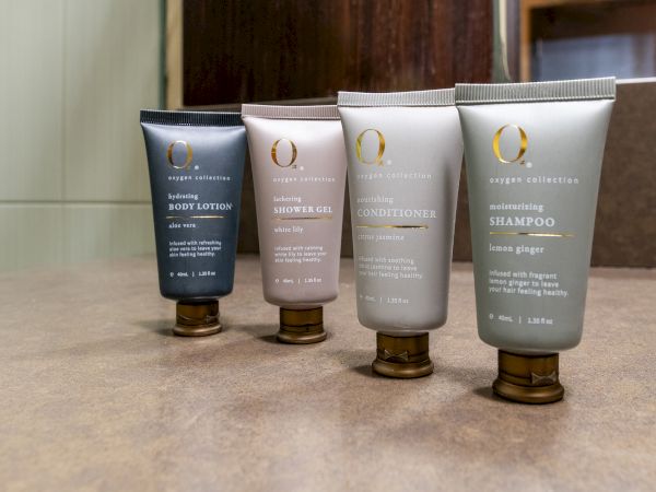 Tubes of body lotion, shower gel, conditioner, and shampoo are arranged on a countertop.